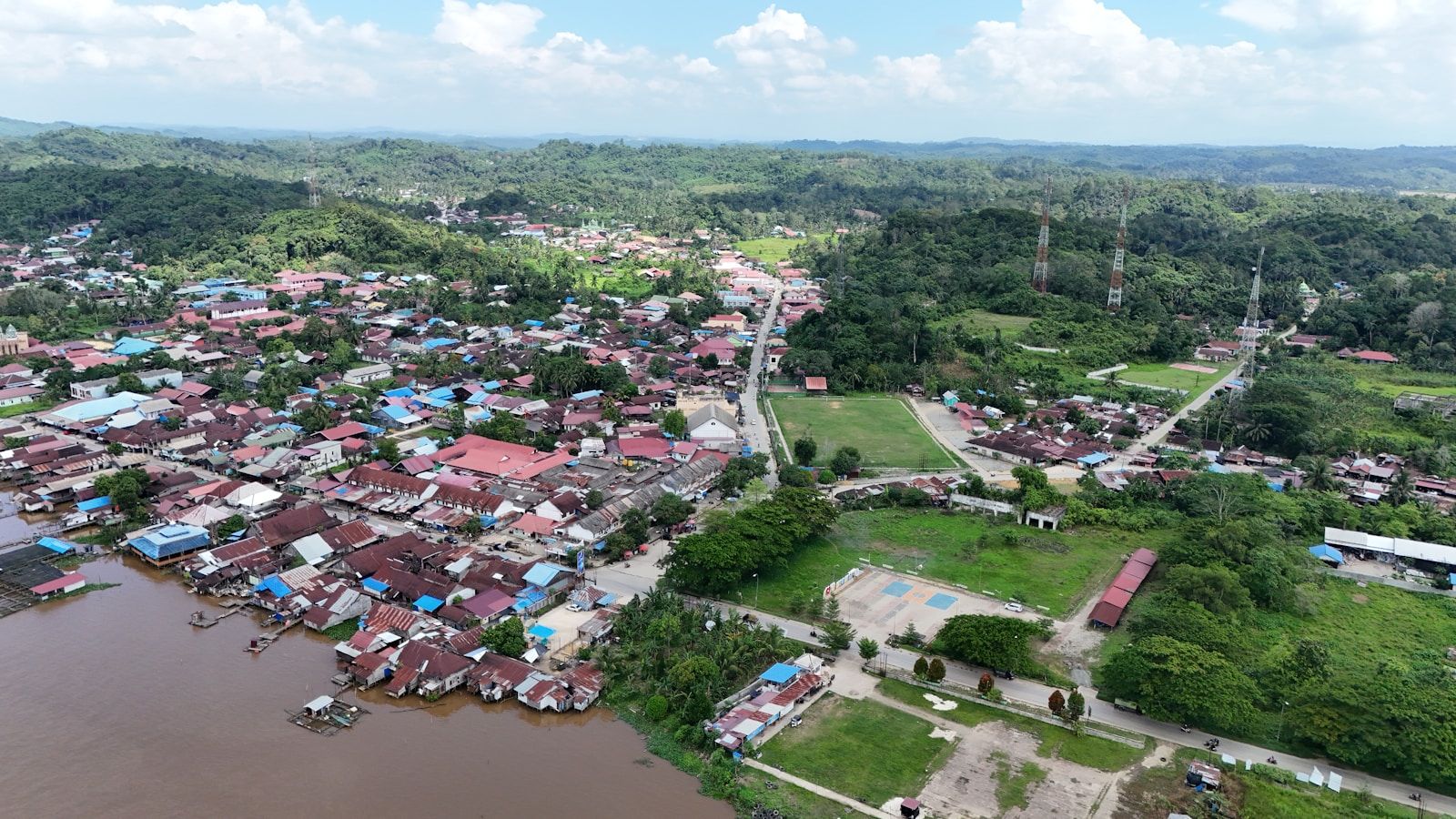 Vista aérea de uma cidade ribeirinha cercada por floresta densa e um rio, remetendo às comunidades do Alto Rio Negro amazônico