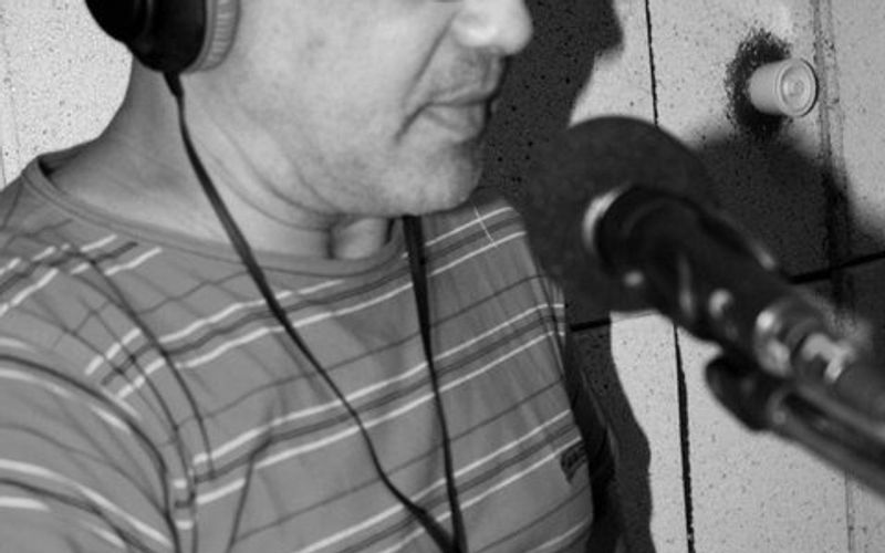 Anselmo Verissimo em estúdio de rádio com fones e microfone