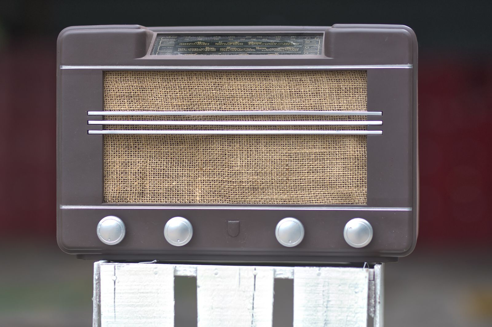 Close de um rádio receptor antigo de madeira, com design retrô, evocando a era de ouro do radiojornalismo brasileiro.