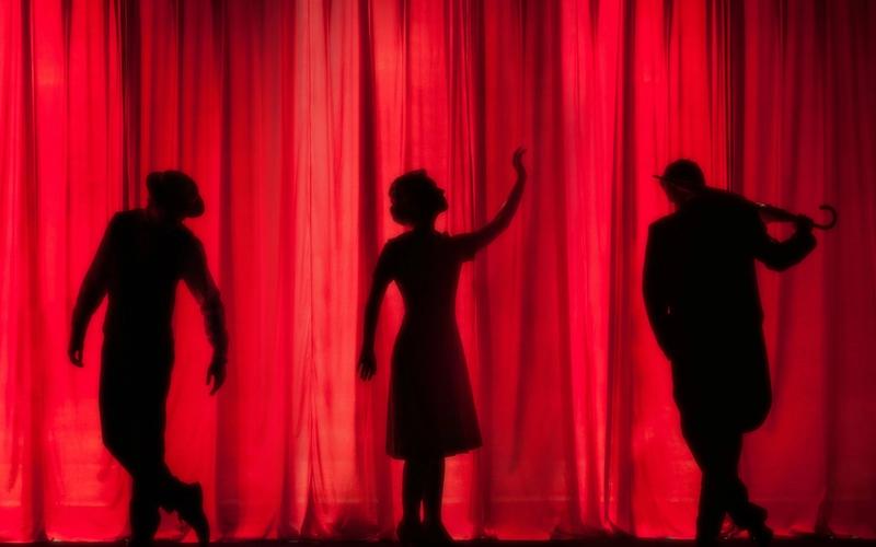 Palco iluminado num teatro vazio antes do espetáculo começar, representando a estrutura concreta por trás da carreira de quem vive de arte no Brasil.