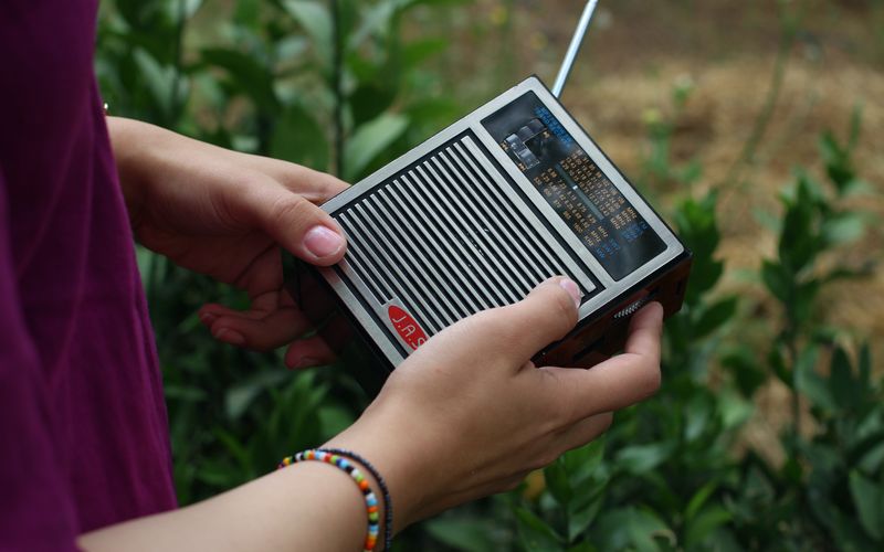 Pessoas reunidas ouvindo transmissão de rádio durante crise ou emergência