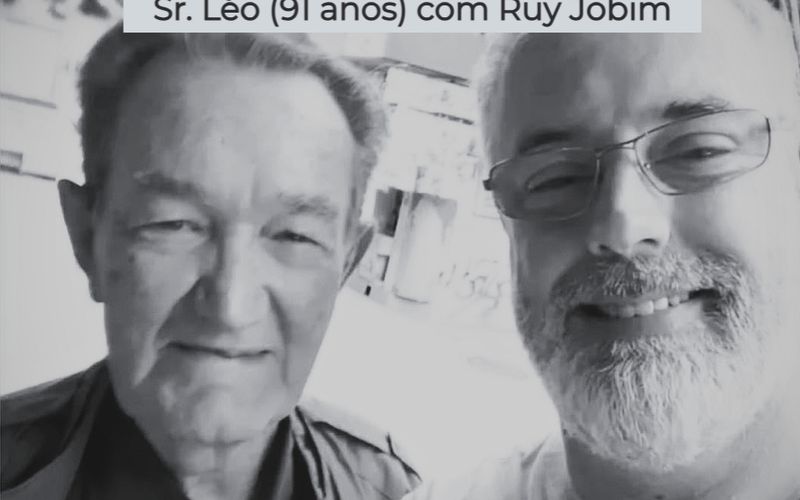 Léo Batista em cabine de transmissão esportiva com microfone ativo