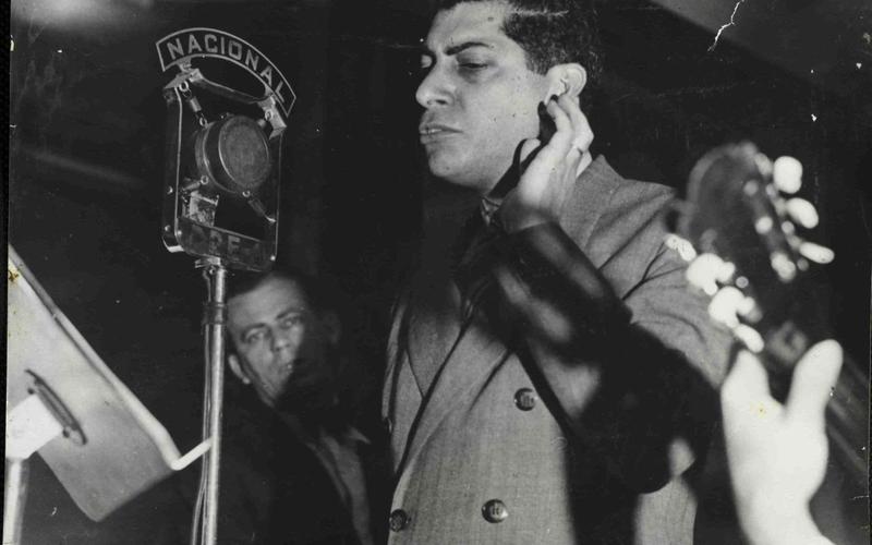Almirante em estúdio de rádio com artistas da MPB ao fundo
