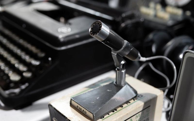 Microfone vintage de transmissão ao lado de uma máquina de escrever antiga, evocando a era das primeiras radiotransmissões esportivas dos anos 1930