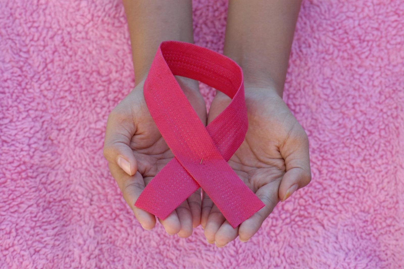 Laço rosa símbolo da campanha Outubro Rosa em fundo vibrante