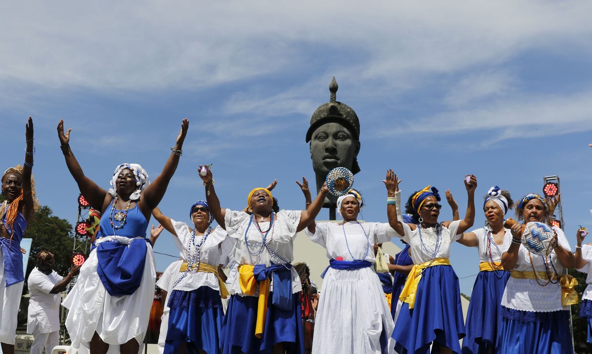 Mulheres e homens negros celebrando com roupas e adornos coloridos