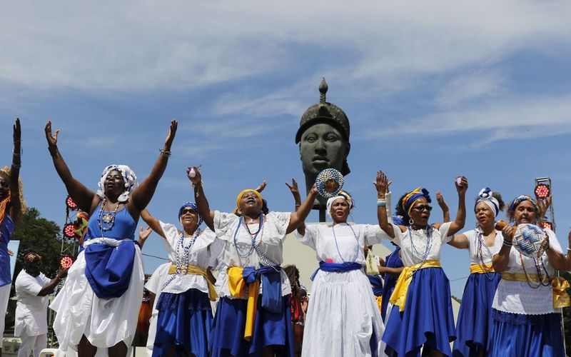 Mulheres e homens negros celebrando com roupas e adornos coloridos