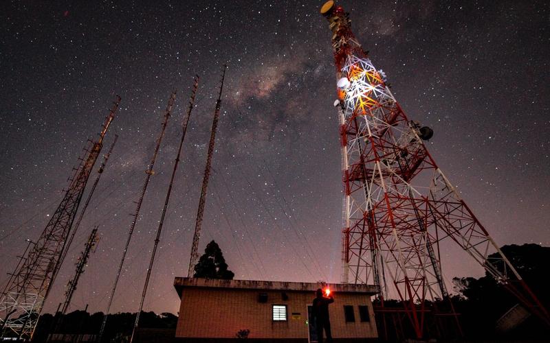 Torres de transmissão de rádio AM estaiadas sob um céu estrelado com a Via Láctea visível, à noite