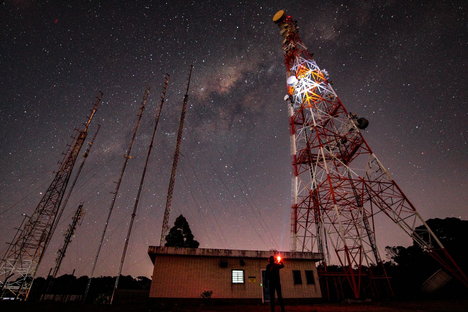 Torres de transmissão de rádio AM estaiadas sob um céu estrelado com a Via Láctea visível, à noite