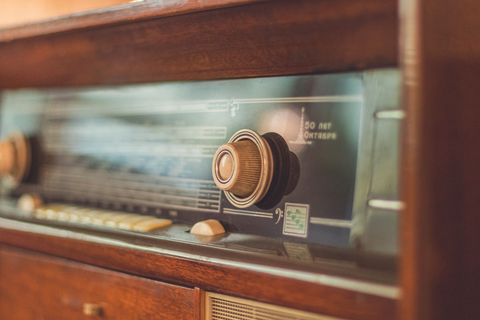 Close-up de um rádio antigo de madeira, com botões dourados e o dial iluminado, evocando a época em que se acompanhavam as Copas do Mundo pela transmissão de rádio