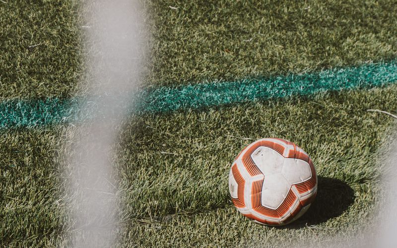 Jogadores em campo durante partida de futebol com torcida ao fundo