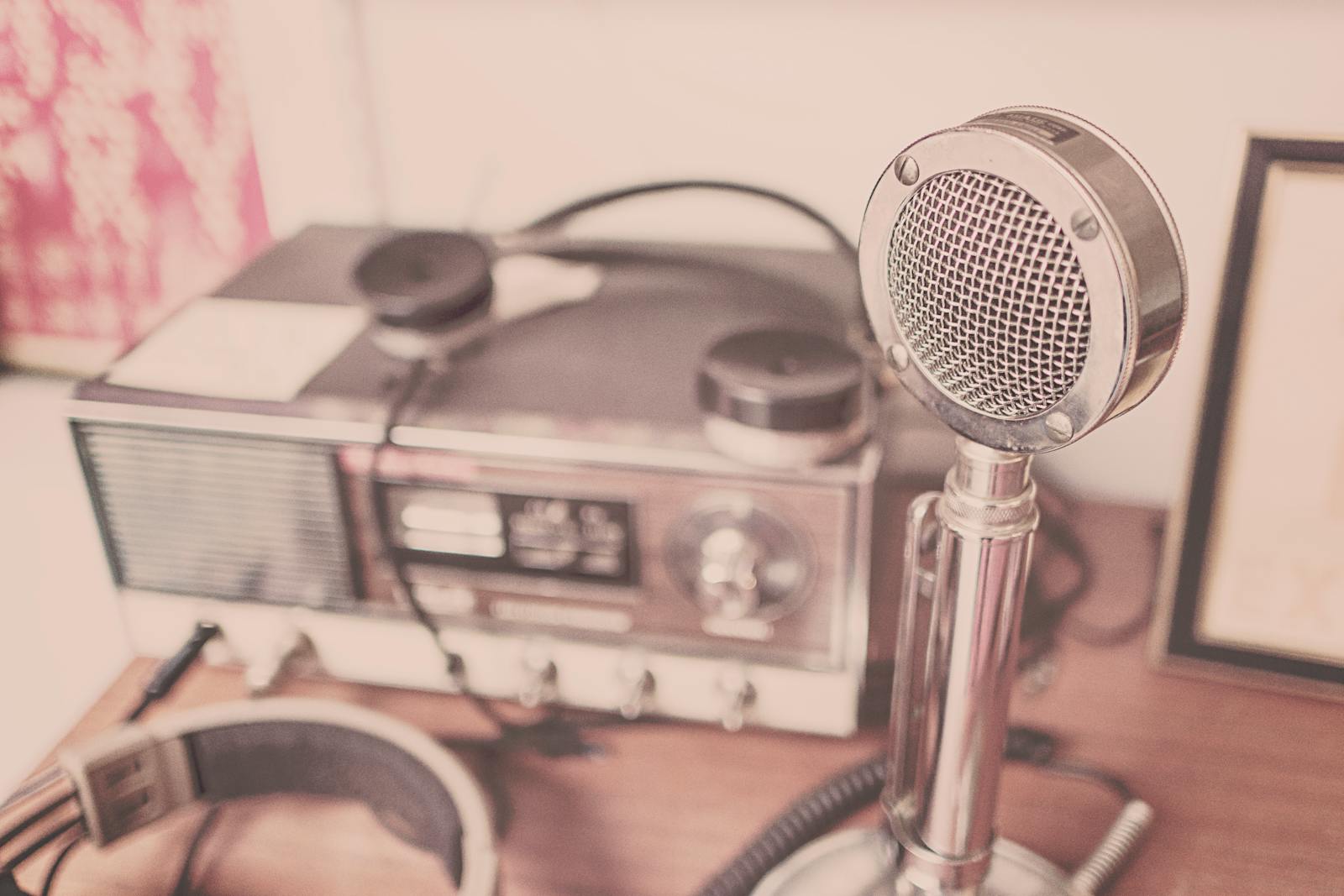 Microfone cromado antigo ao lado de um rádio receptor clássico, em tom sépia nostálgico, evocando a era de ouro da locução.