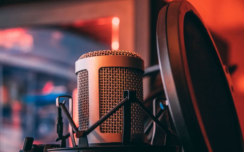 Locutor em estúdio controlando respiração durante gravação profissional.
