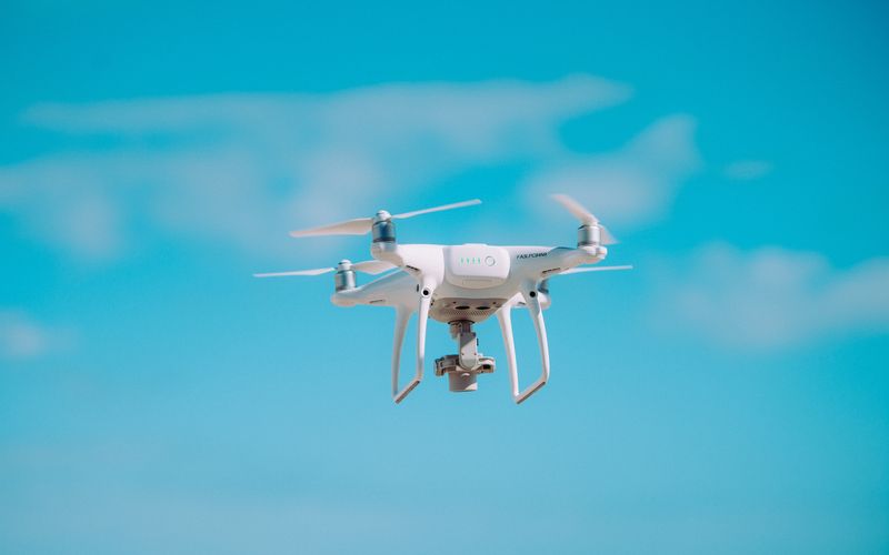 Drone amarelo sobrevoando área urbana em teste de entrega aérea