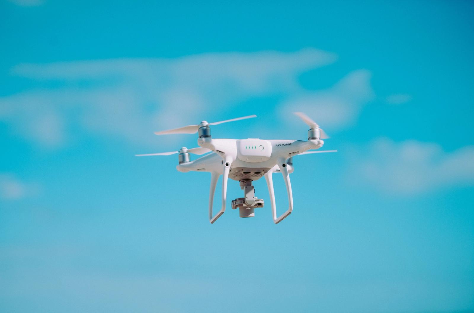 Drone amarelo sobrevoando área urbana em teste de entrega aérea