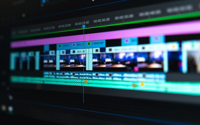 Estação de edição com vários monitores e telas de trabalho, simbolizando a produção multiplataforma que desdobra um mesmo conteúdo em rádio, podcast, vídeo e cortes para redes sociais.