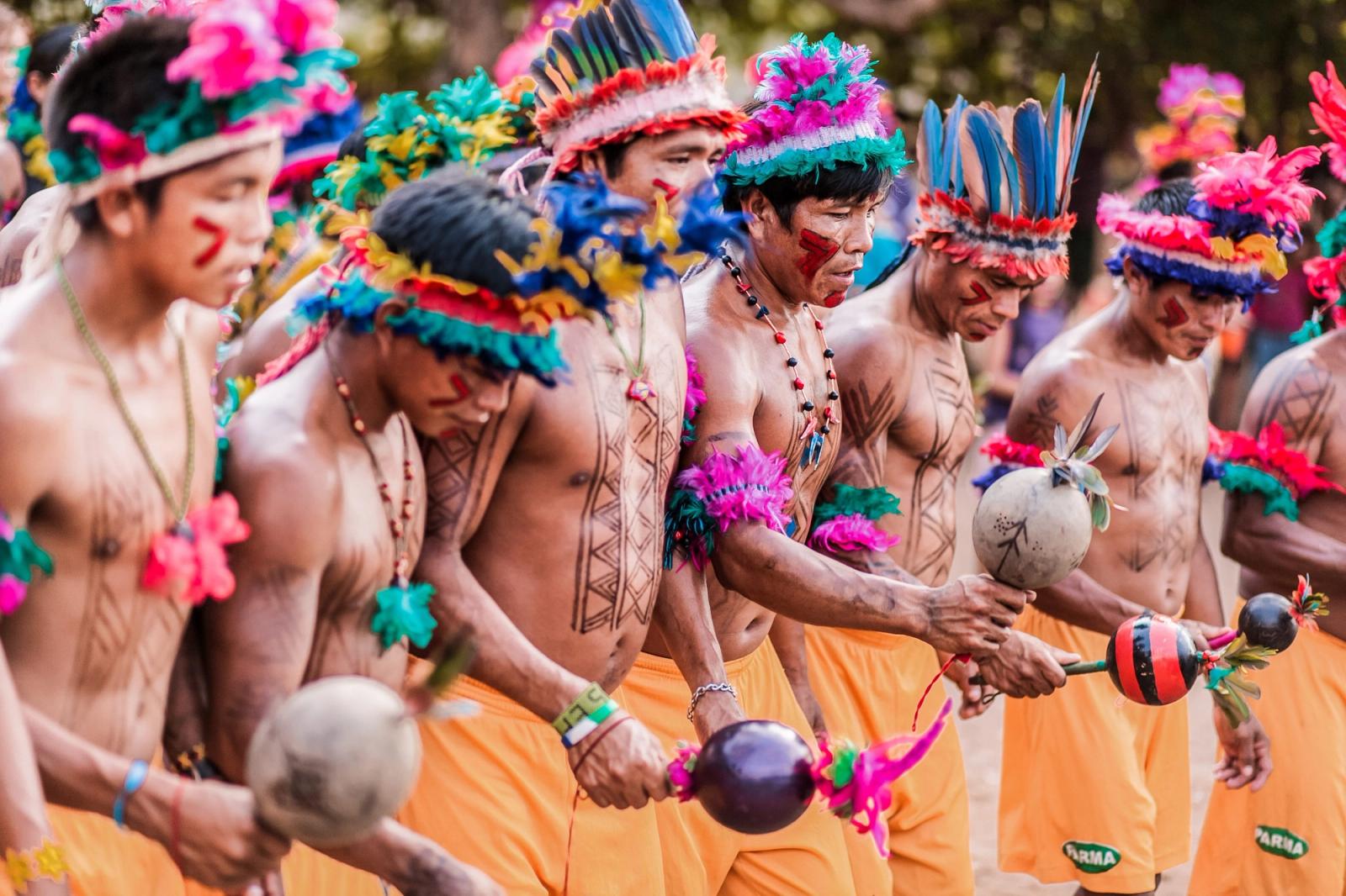 Povos indígenas em celebração cultural com ornamentos e símbolos tradicionais