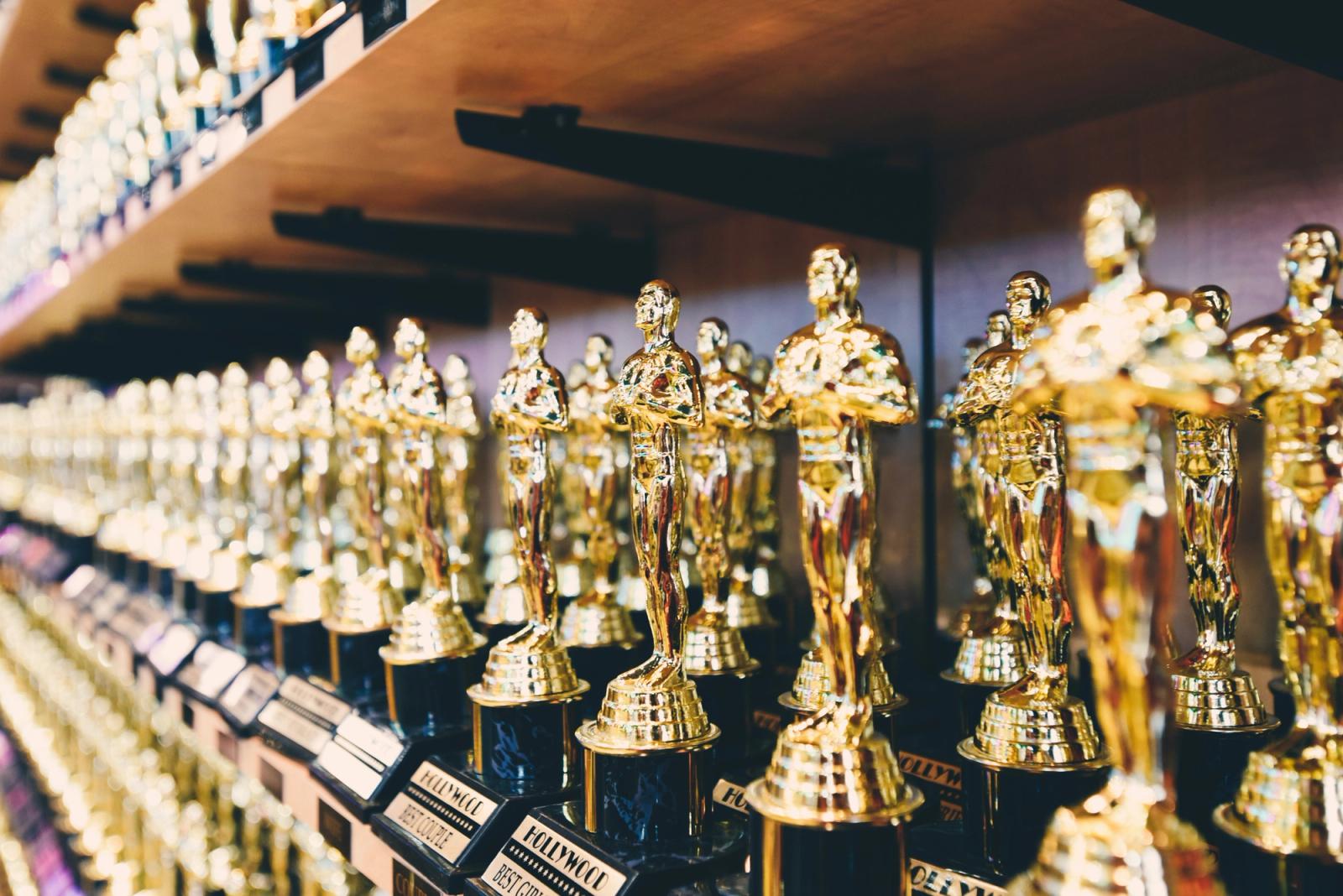 Palco do Oscar com iluminação dramática e estatuetas douradas brilhando