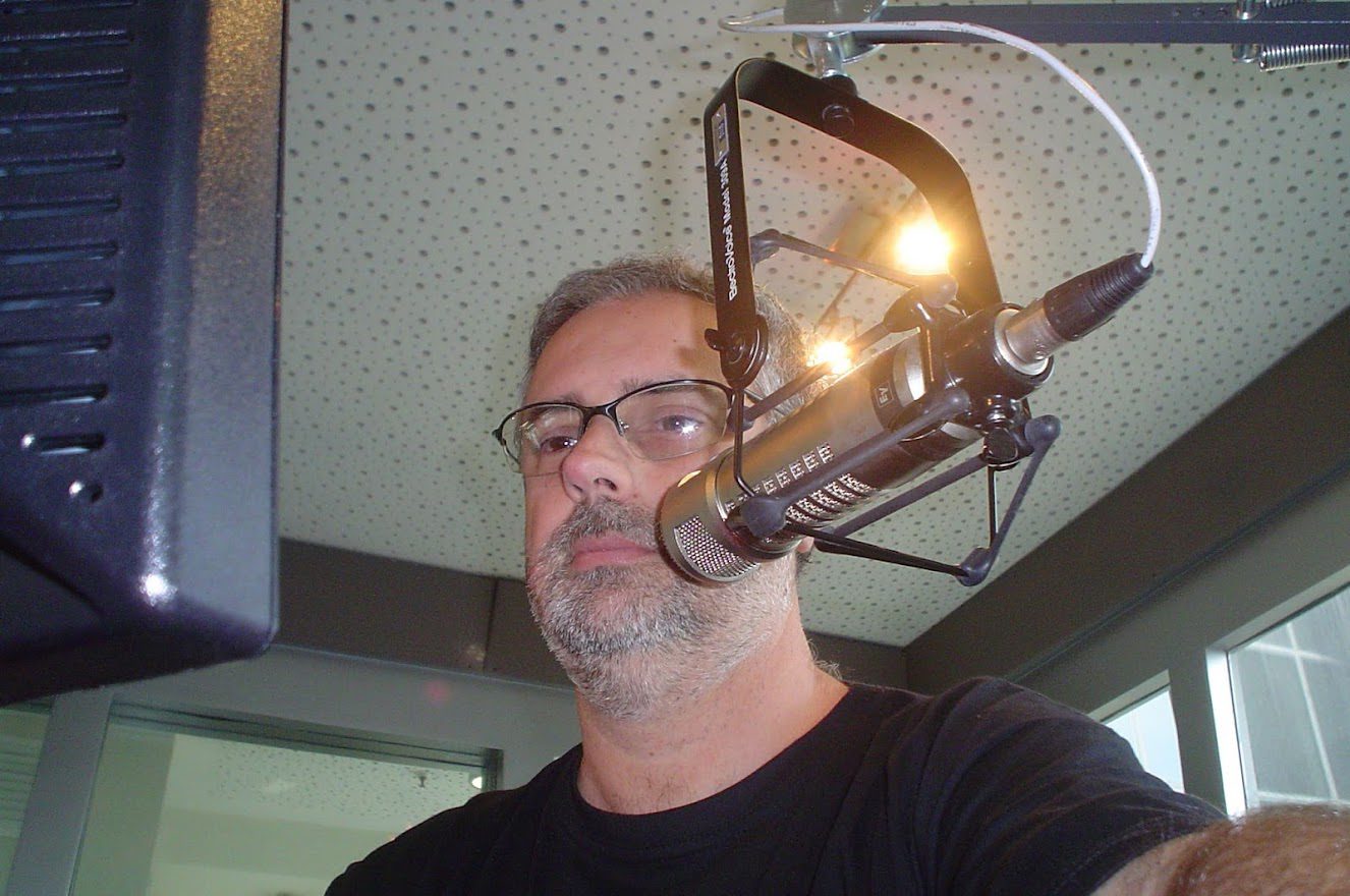 Locutor em cabine de estúdio com microfone e equipamentos