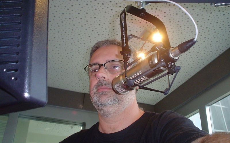 Locutor em cabine de estúdio com microfone e equipamentos