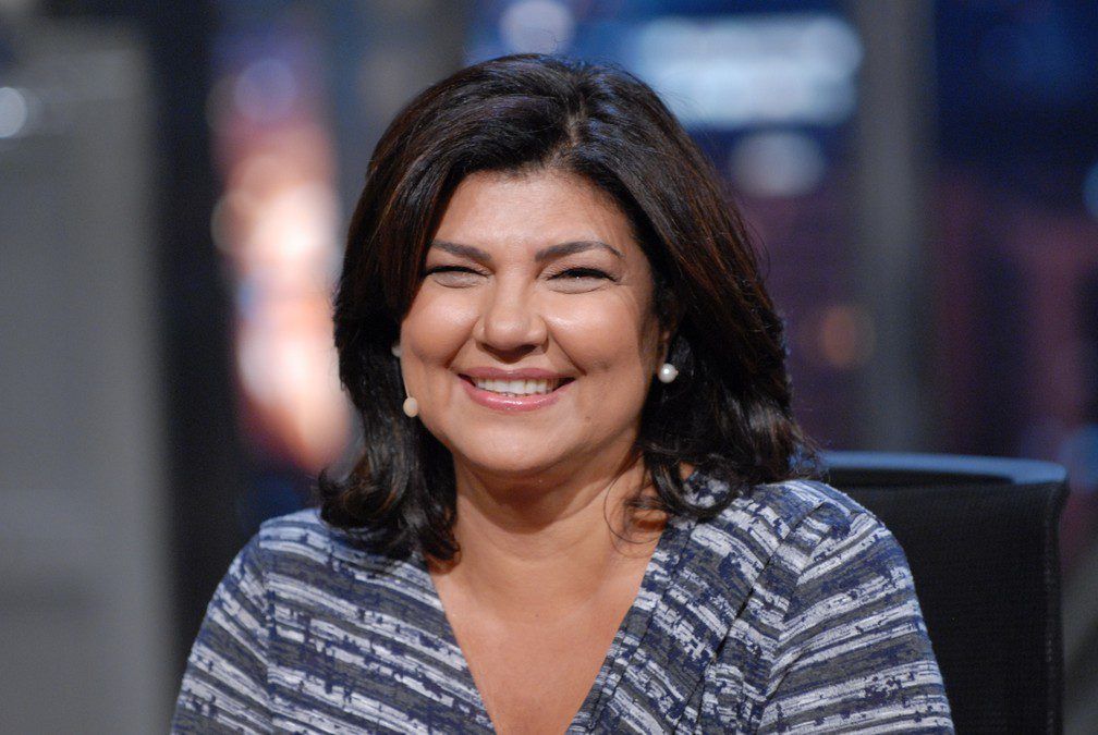 Mulher sorrindo em foto profissional de jornalista com fundo neutro
