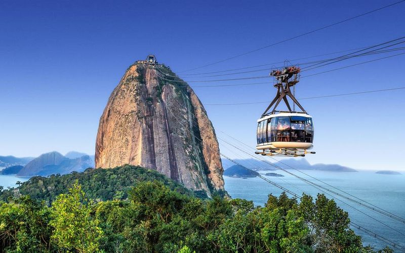 Bondinho vermelho do Pão de Açúcar em trajeto aéreo sobre a baía