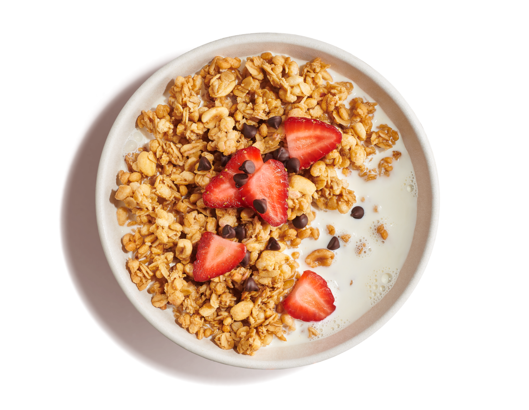 White bowl of milk with golden crunchy granola topped with mini chocolate chips and cut strawberries on an orange background.