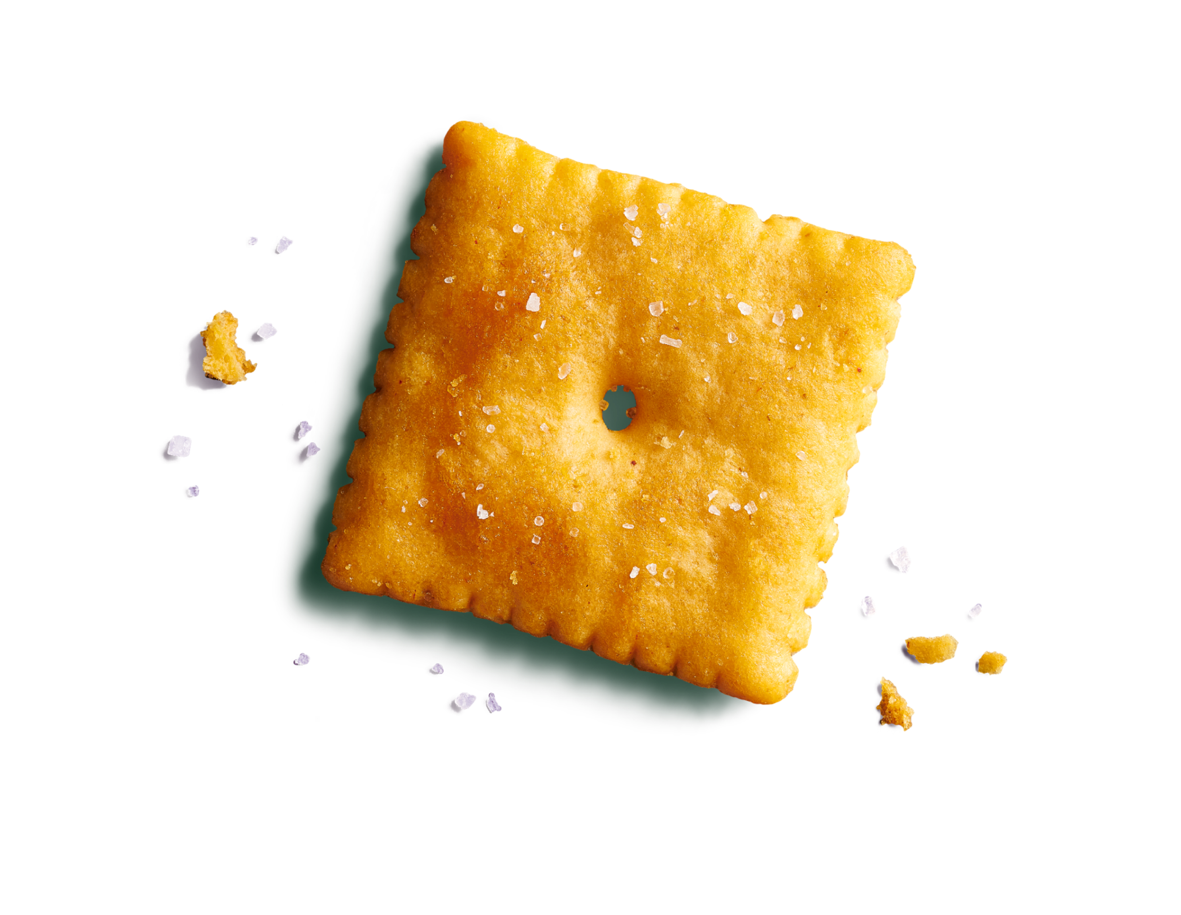 Close-up of one large cheesy, orange square cracker on a vibrant seafoam green background with salt flakes and cheese crumbs.