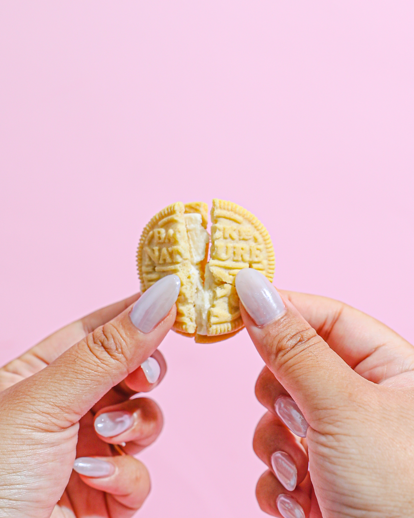 A golden creme cookie being snapped in half