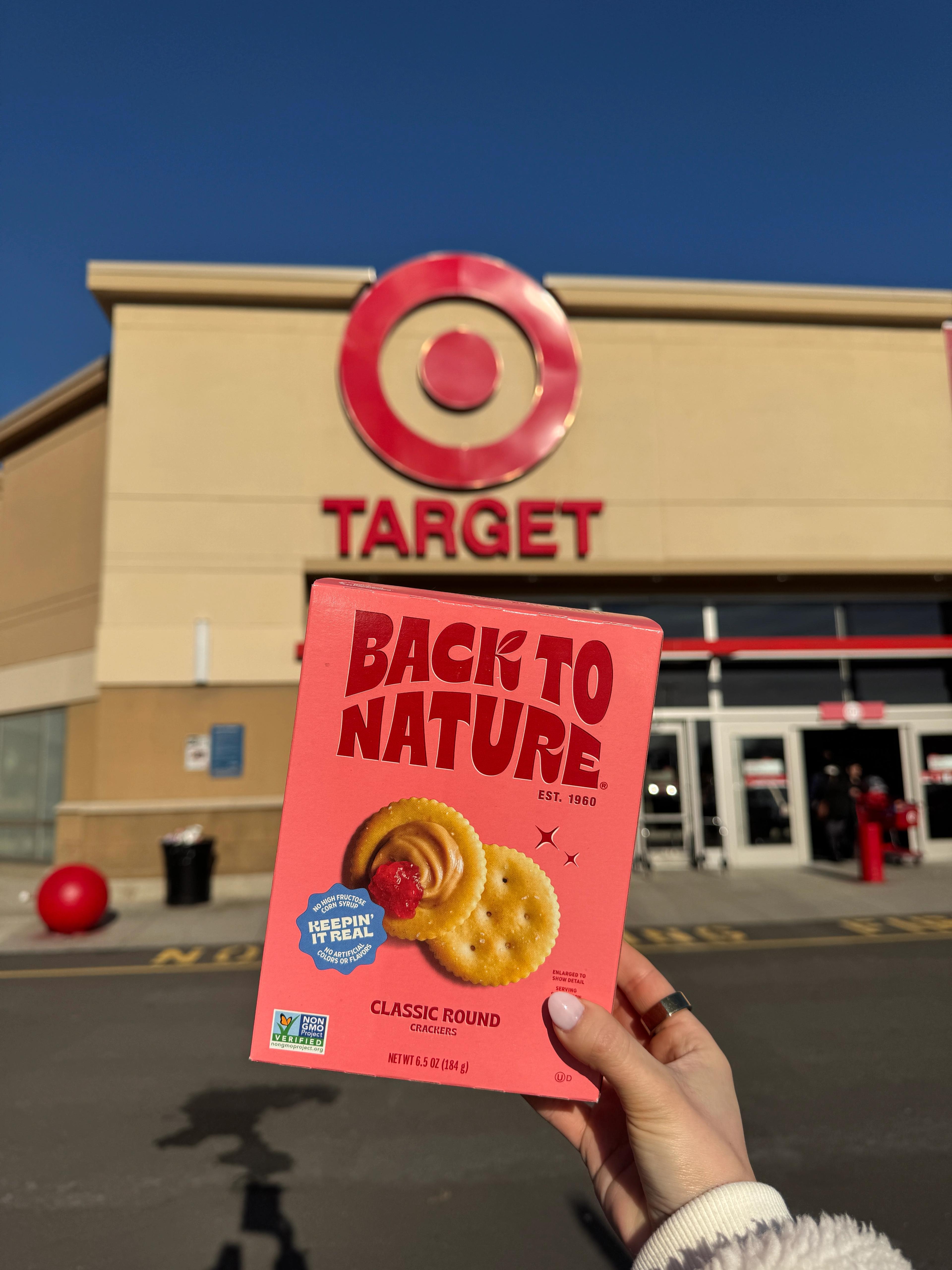 A hand holding back to nature classic round crackers outside a Target store
