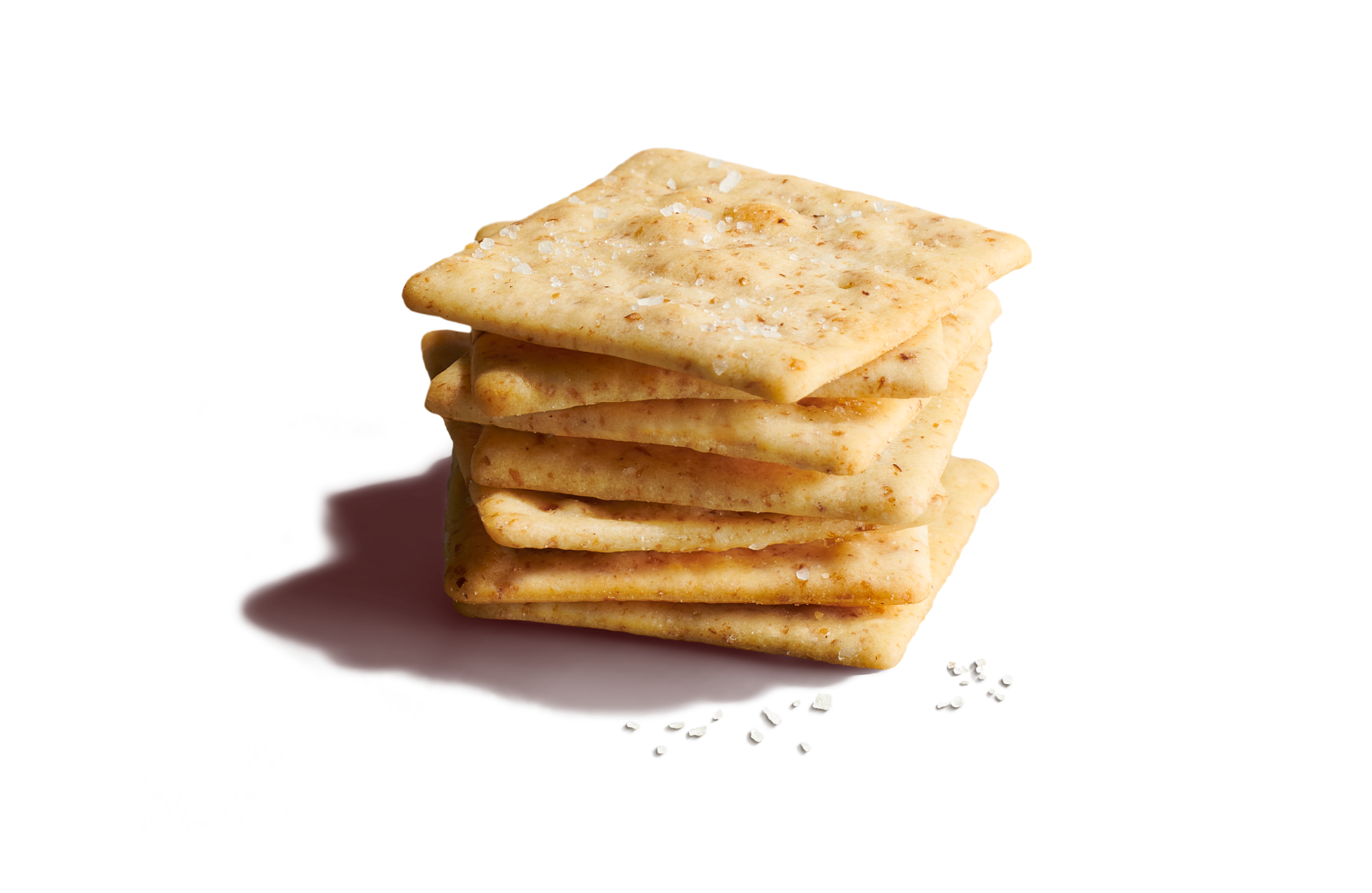 Close-up stack of seven square, crispy salted wheat crackers on a vibrant yellow background with scattered sea salt flakes.