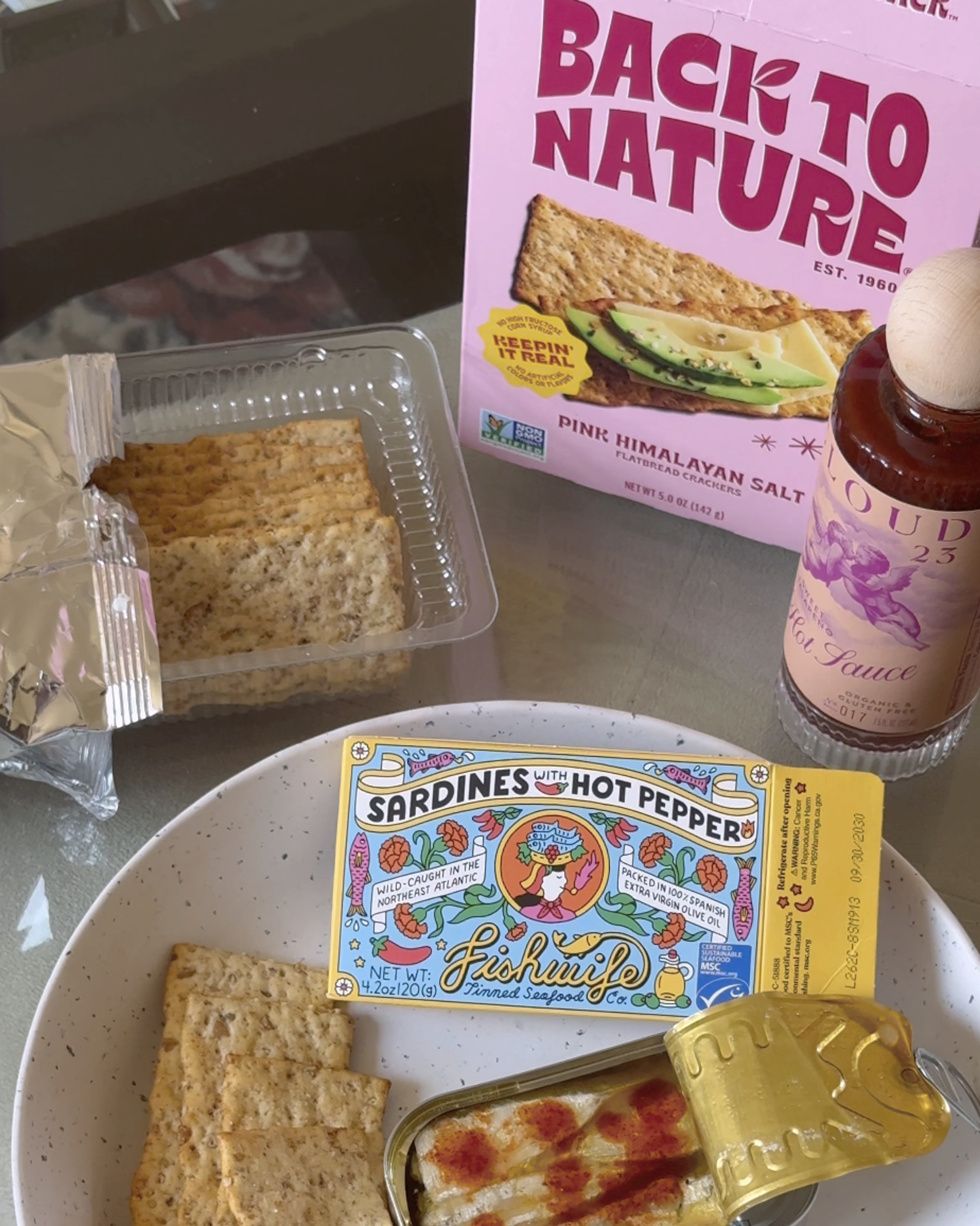 Back to Nature pink himalayan salt flatbread crackers with fishwife tinned fish and cloud 23 hot sauce on a snack plate