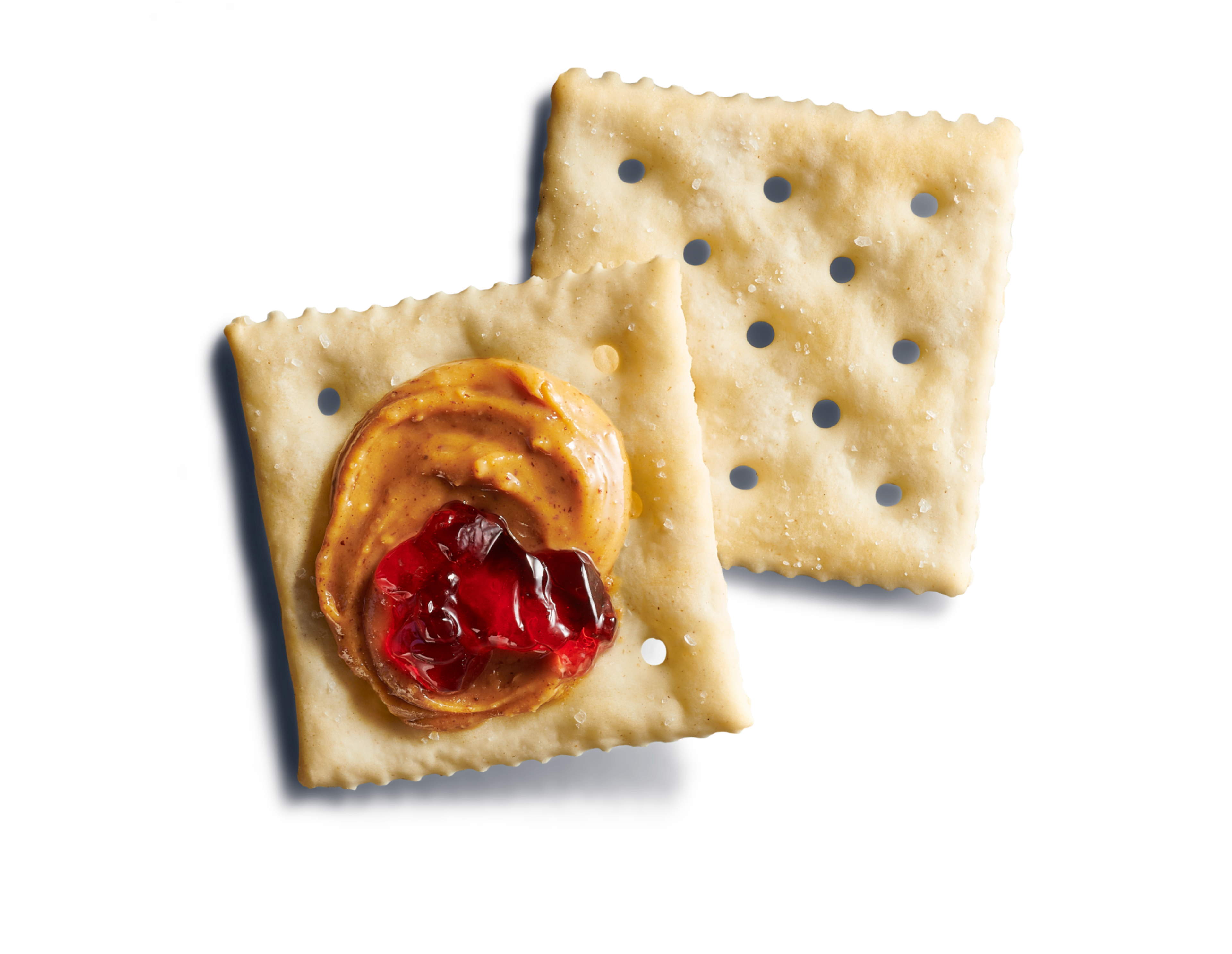 Close-up of two large square, light saltine crackers on a blue background with a peanut butter and jelly dollop. 