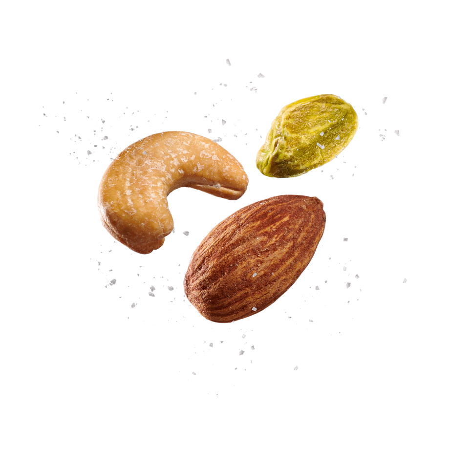 Three nuts, one whole almond, one cashew, and one shelled pistachio, with salt float on a green background