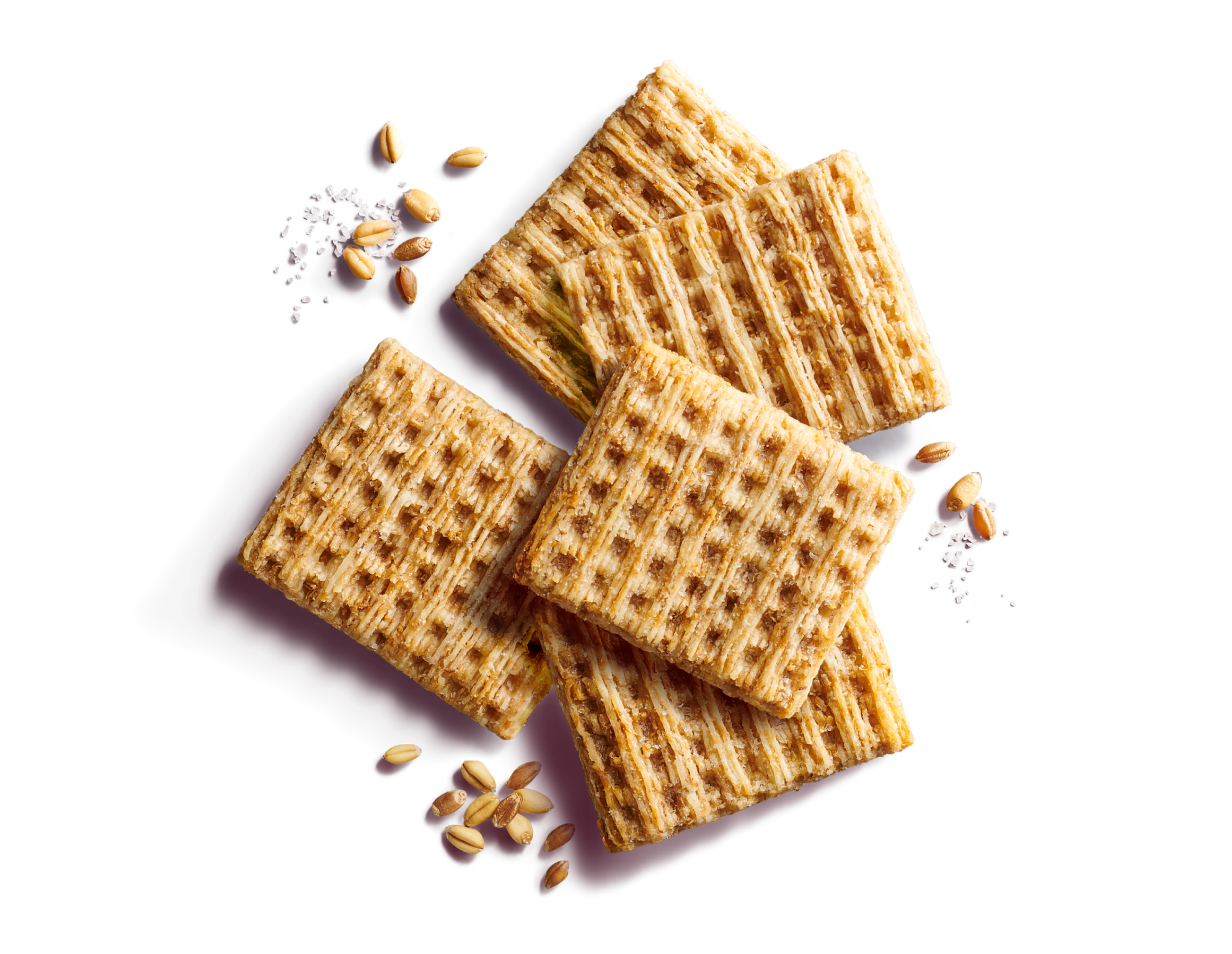 Close-up of five scattered whole grain, woven wheat crackers on a purple background with wheat grains and sea salt flakes.