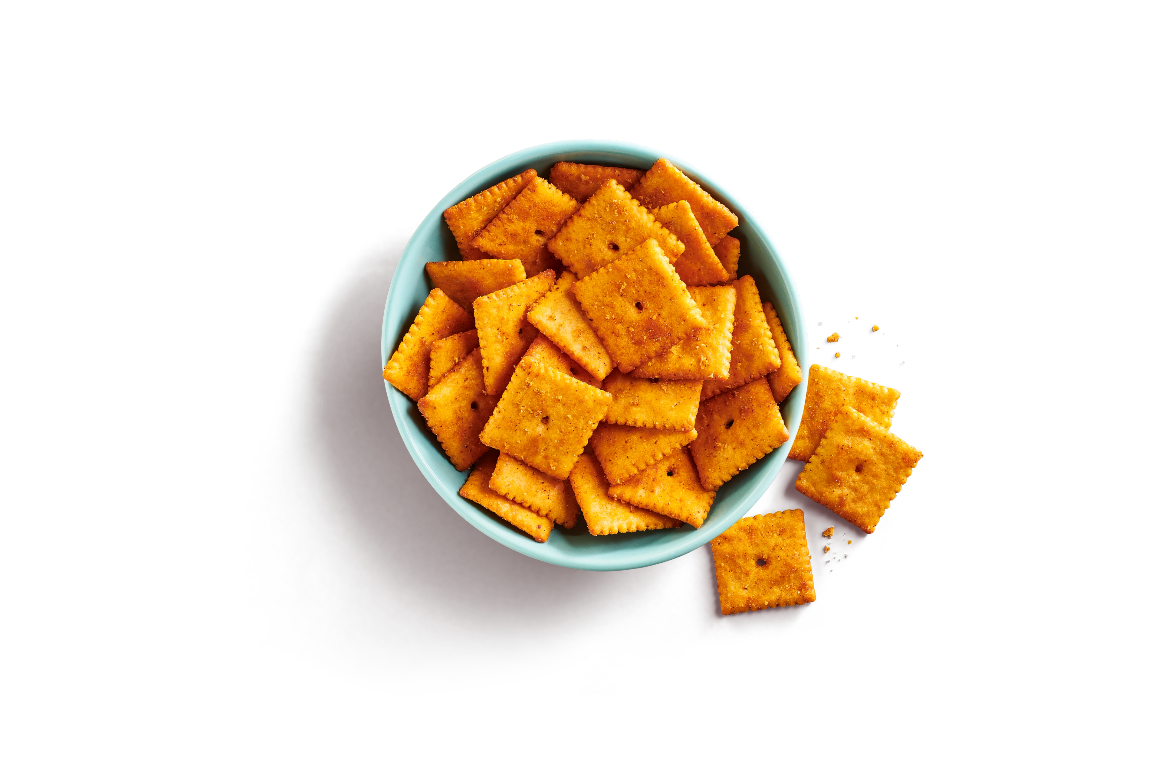 Close-up of a bowl of hot & spicy cheezy crackers with specks of red seasoning visible.