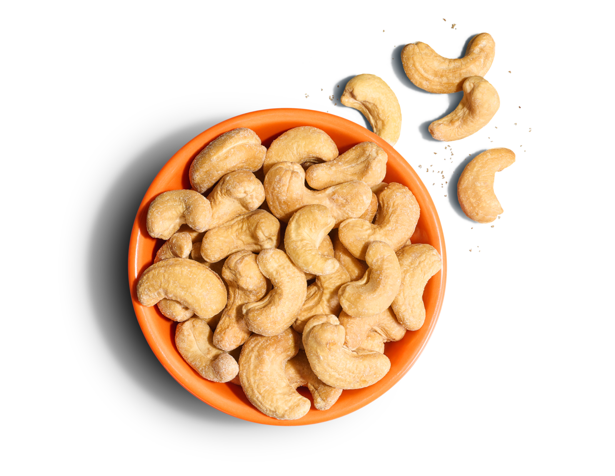 Bright orange bowl of whole cashews with sea salt flakes on a bright blue background.