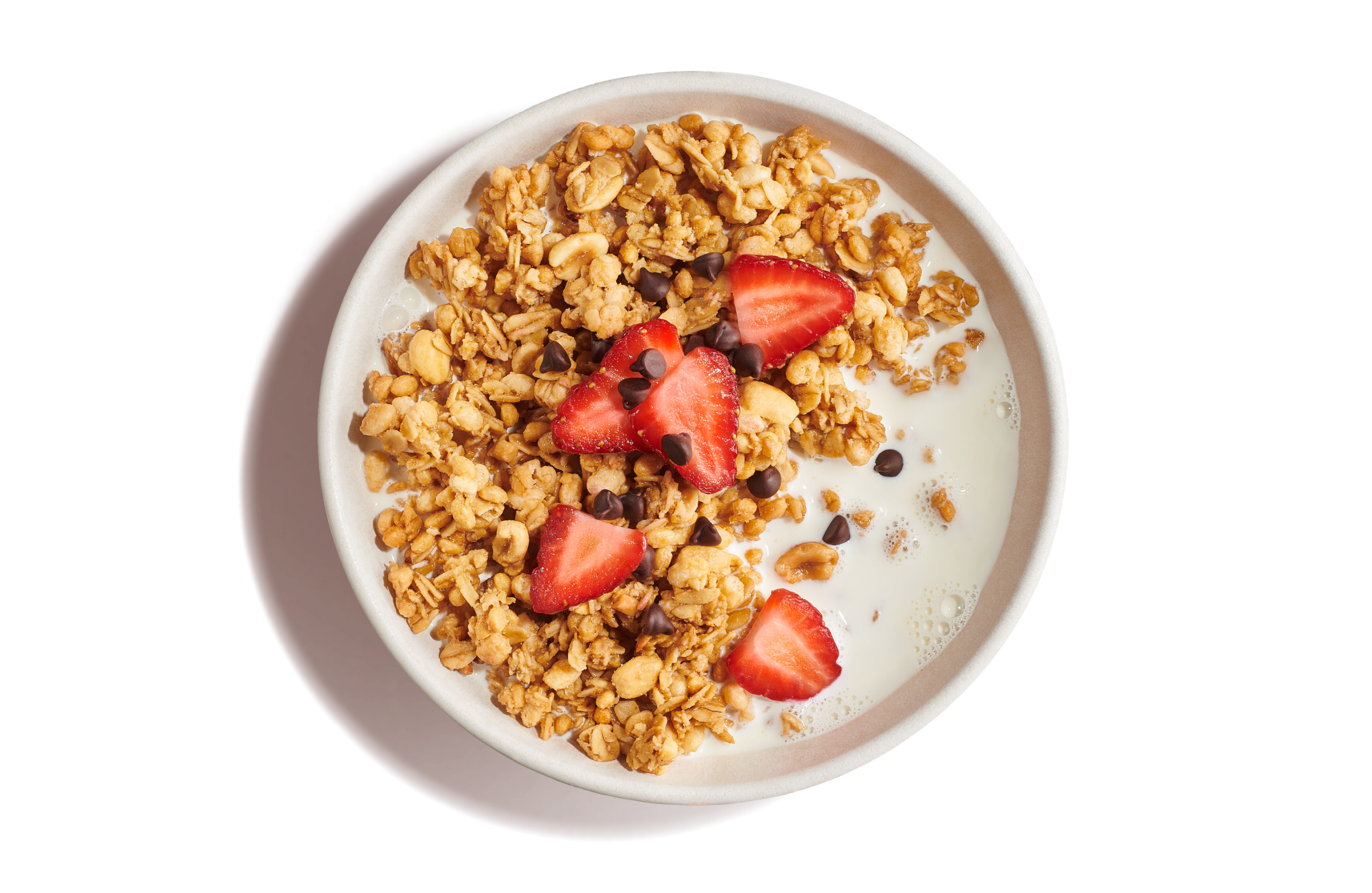 White bowl of milk with golden crunchy granola topped with mini chocolate chips and cut strawberries on an orange background.