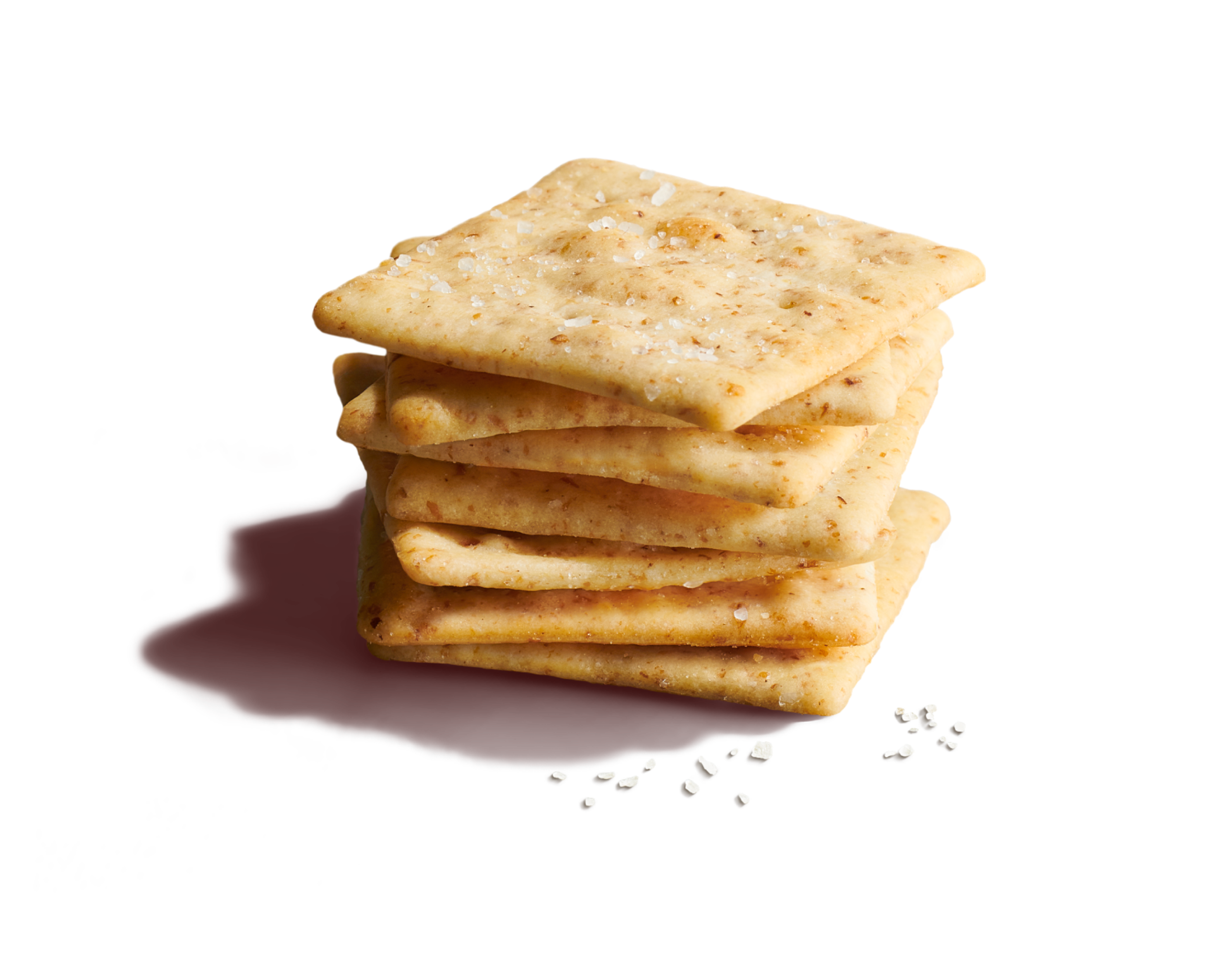 Close-up stack of seven square, crispy salted wheat crackers on a vibrant yellow background with scattered sea salt flakes.