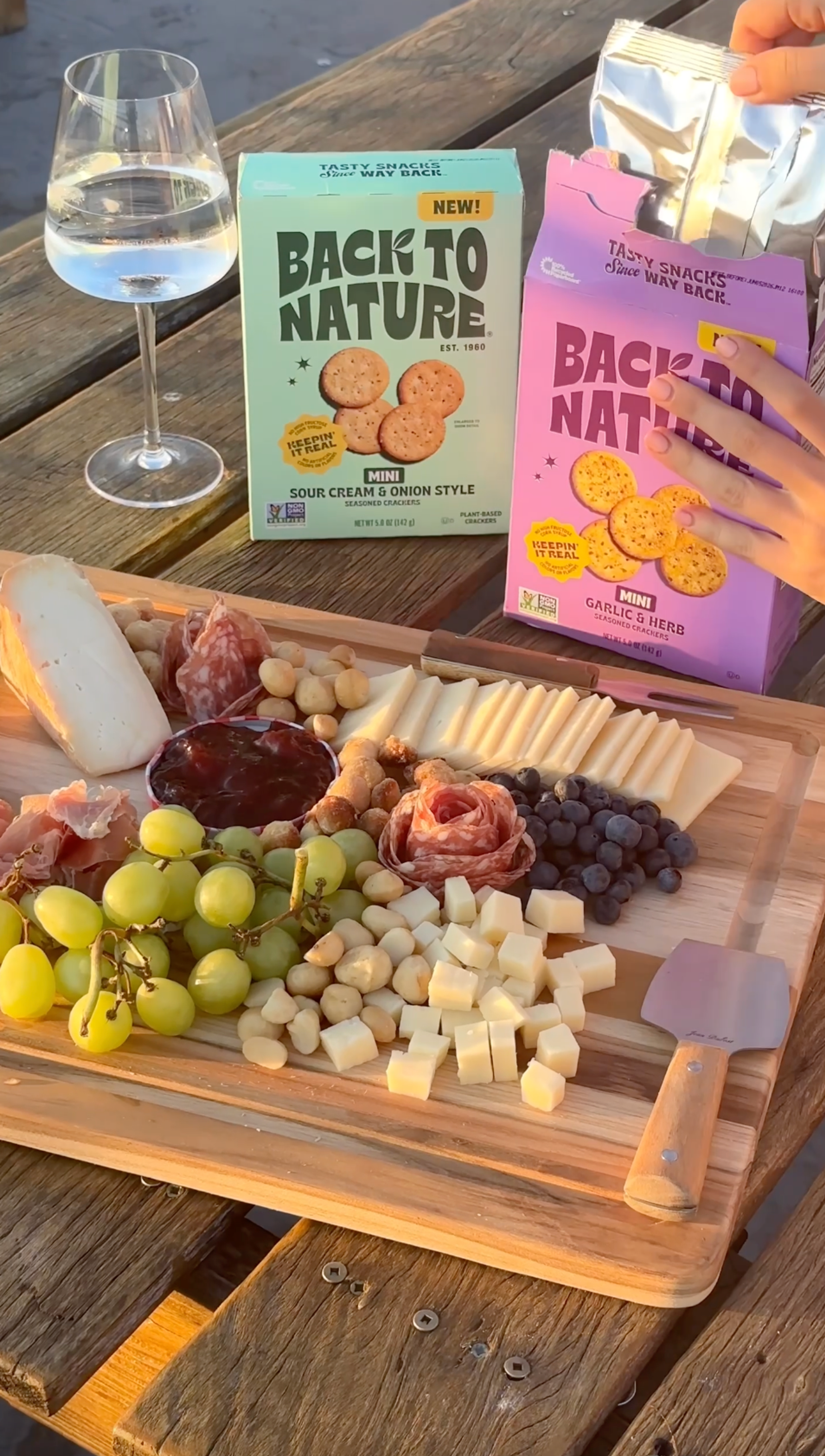 A snack board with cheeses, fruits, meats and back to nature crackers.