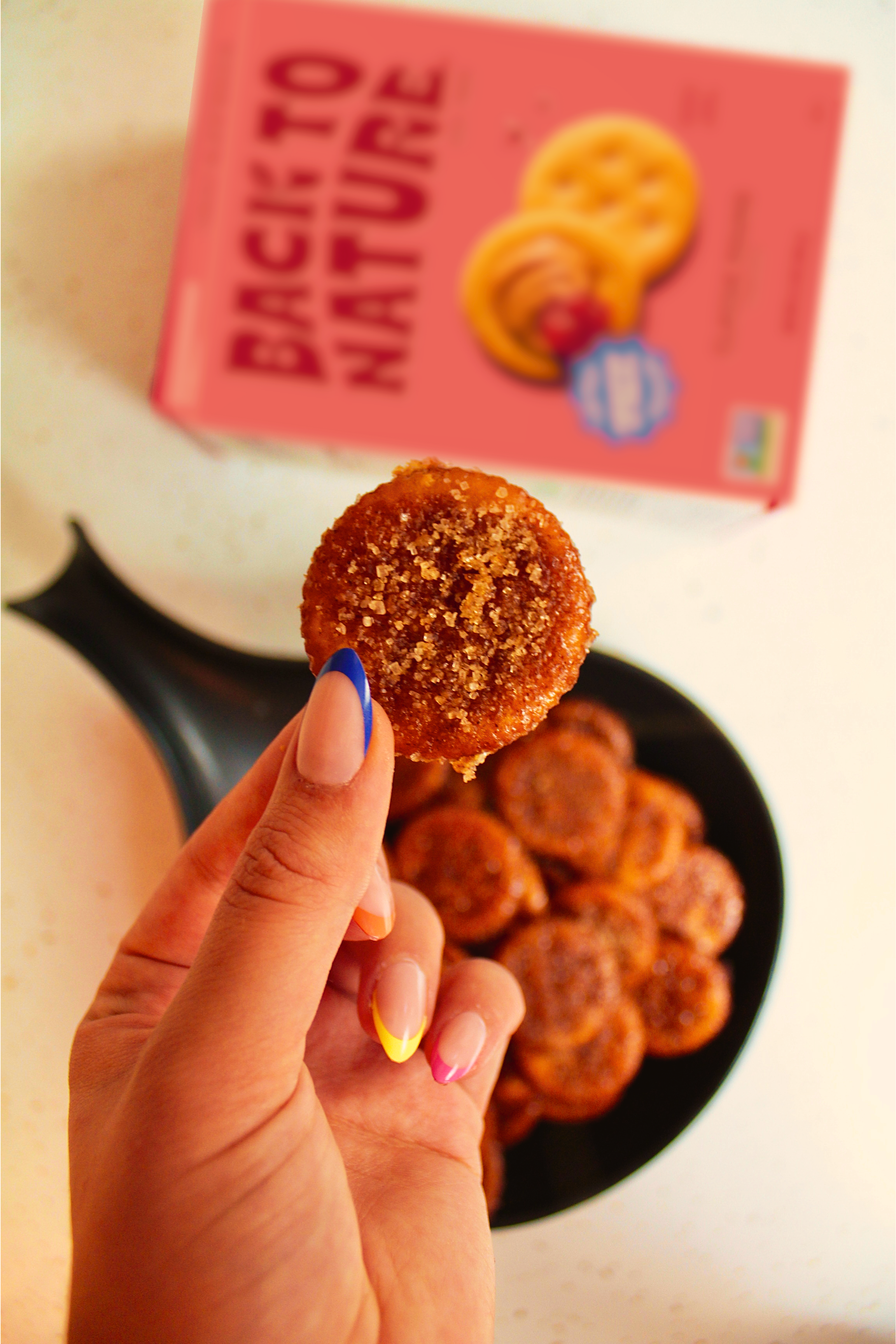 A hand holding a baked churro cracker