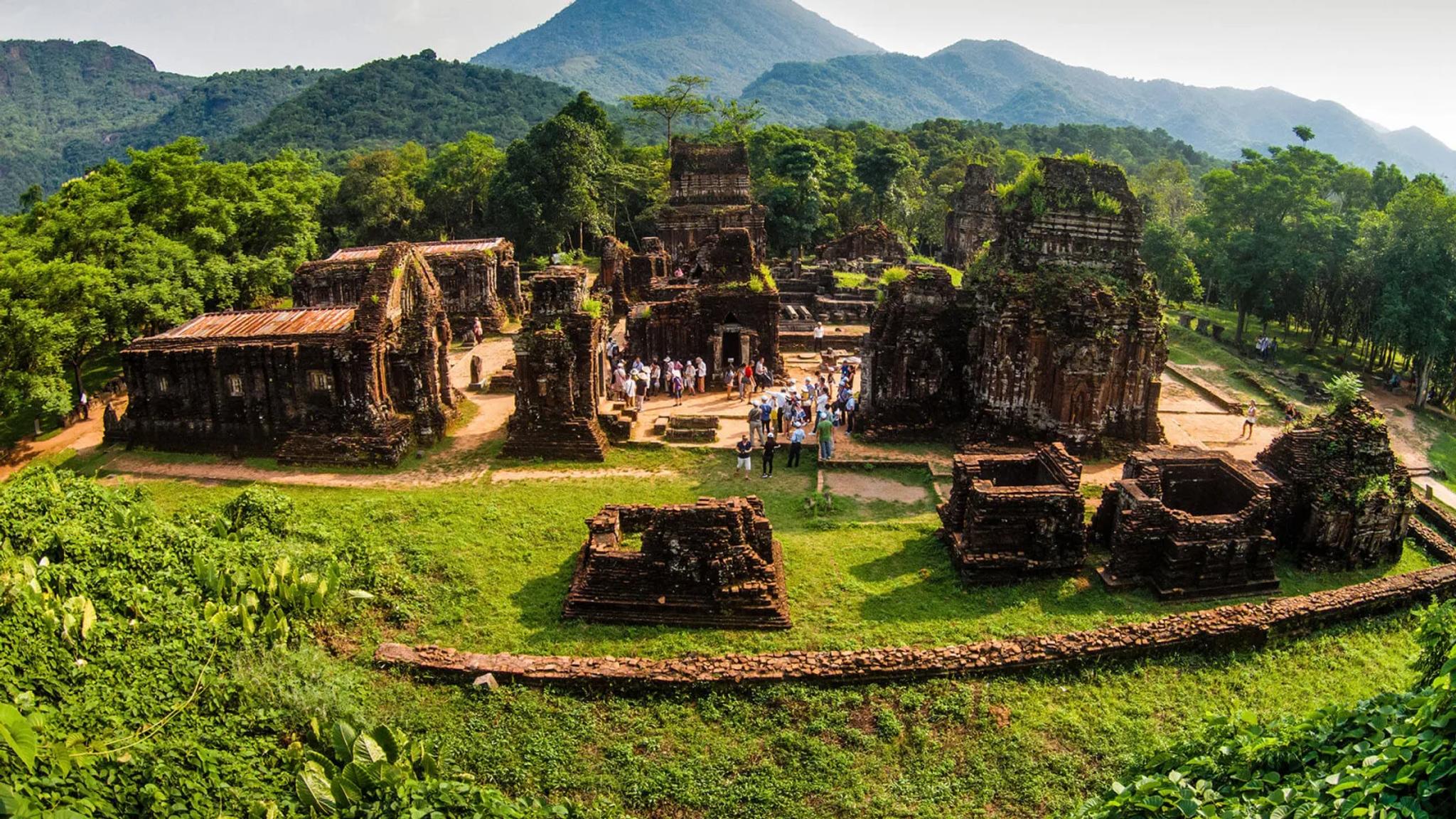 Panorama of the My Son Sanctuary valley with Cham temple clusters, lawns and mountains.
