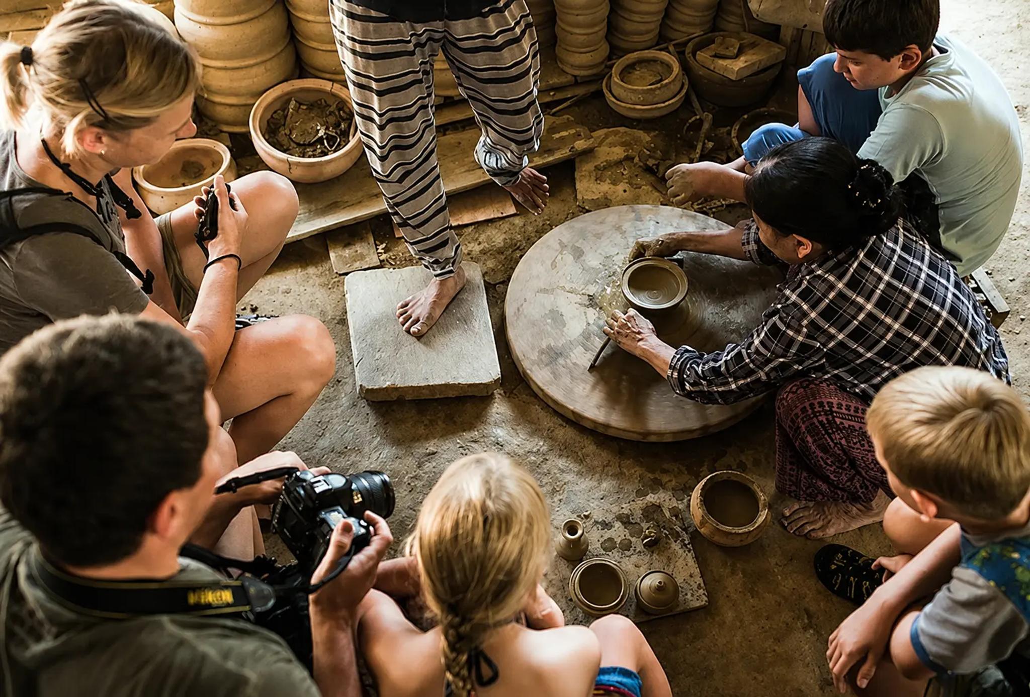 Guests watching a Thanh Ha potter shape clay by hand on the wheel during a Hoi An full-day Old Town and villages tour.