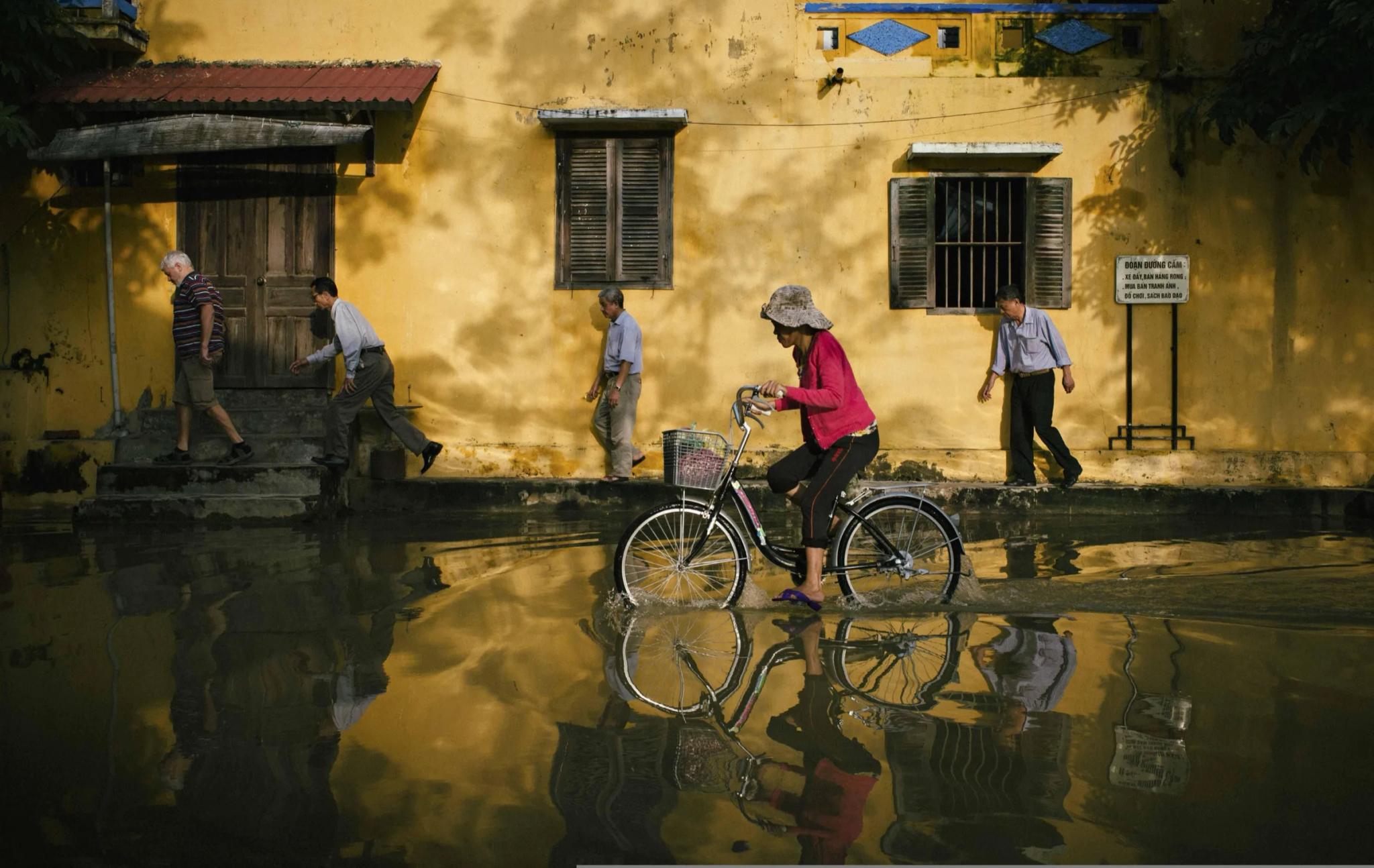 a cyclist rides through a flooded street