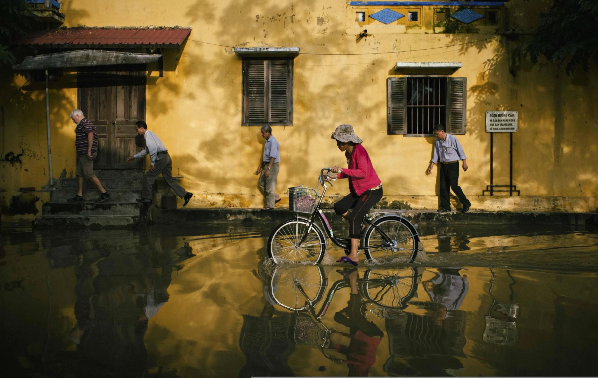 a cyclist rides through a flooded street