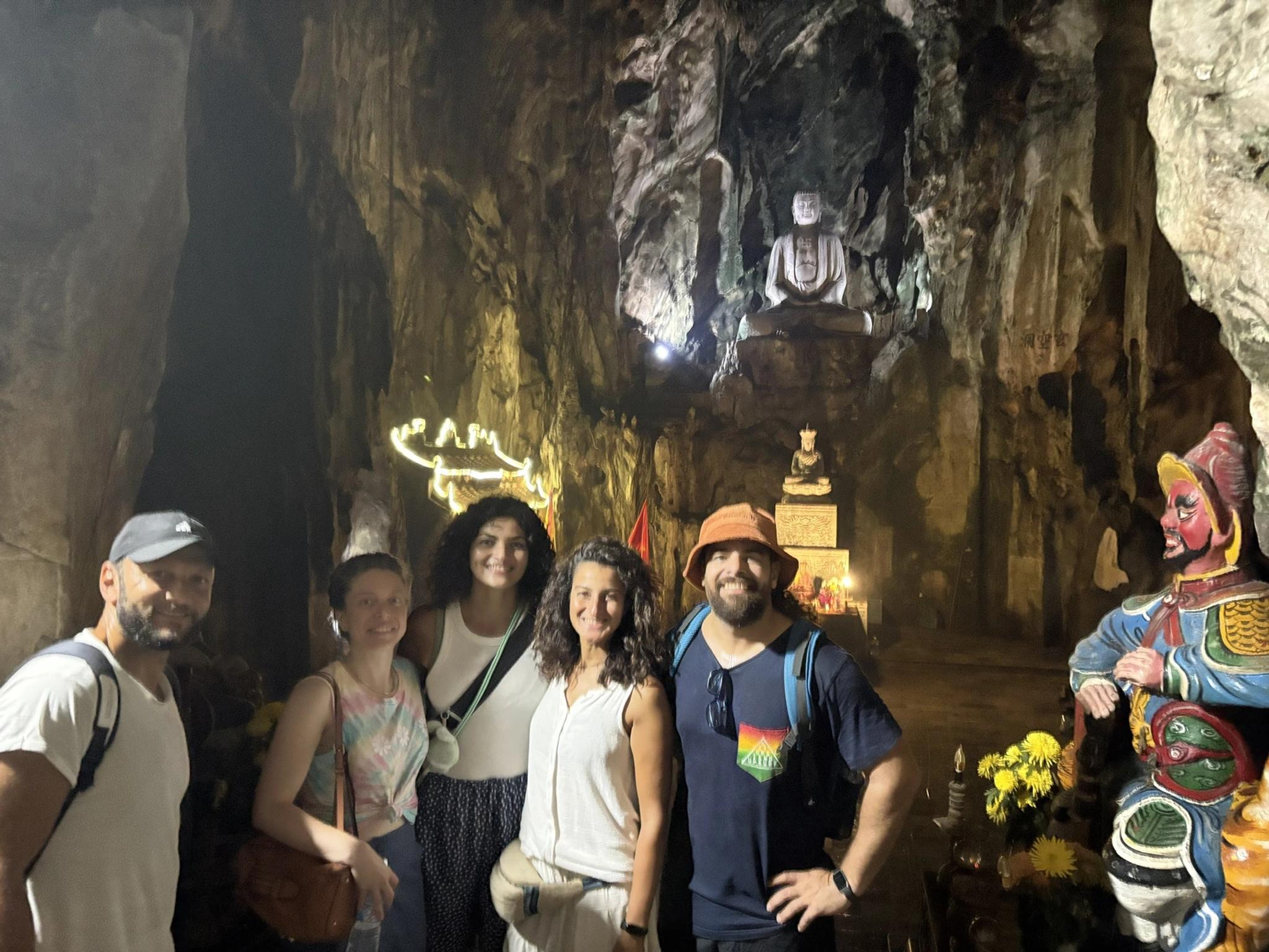 Travellers inside Huyen Khong Cave at the Marble Mountains, with the Buddha statue lit above them, on a Da Nang city highlights day trip from Hoi An.