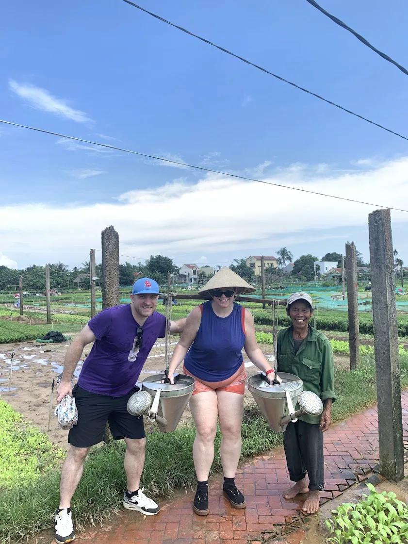 Fin with guests at Tra Que herb village, framed by the vegetable gardens.