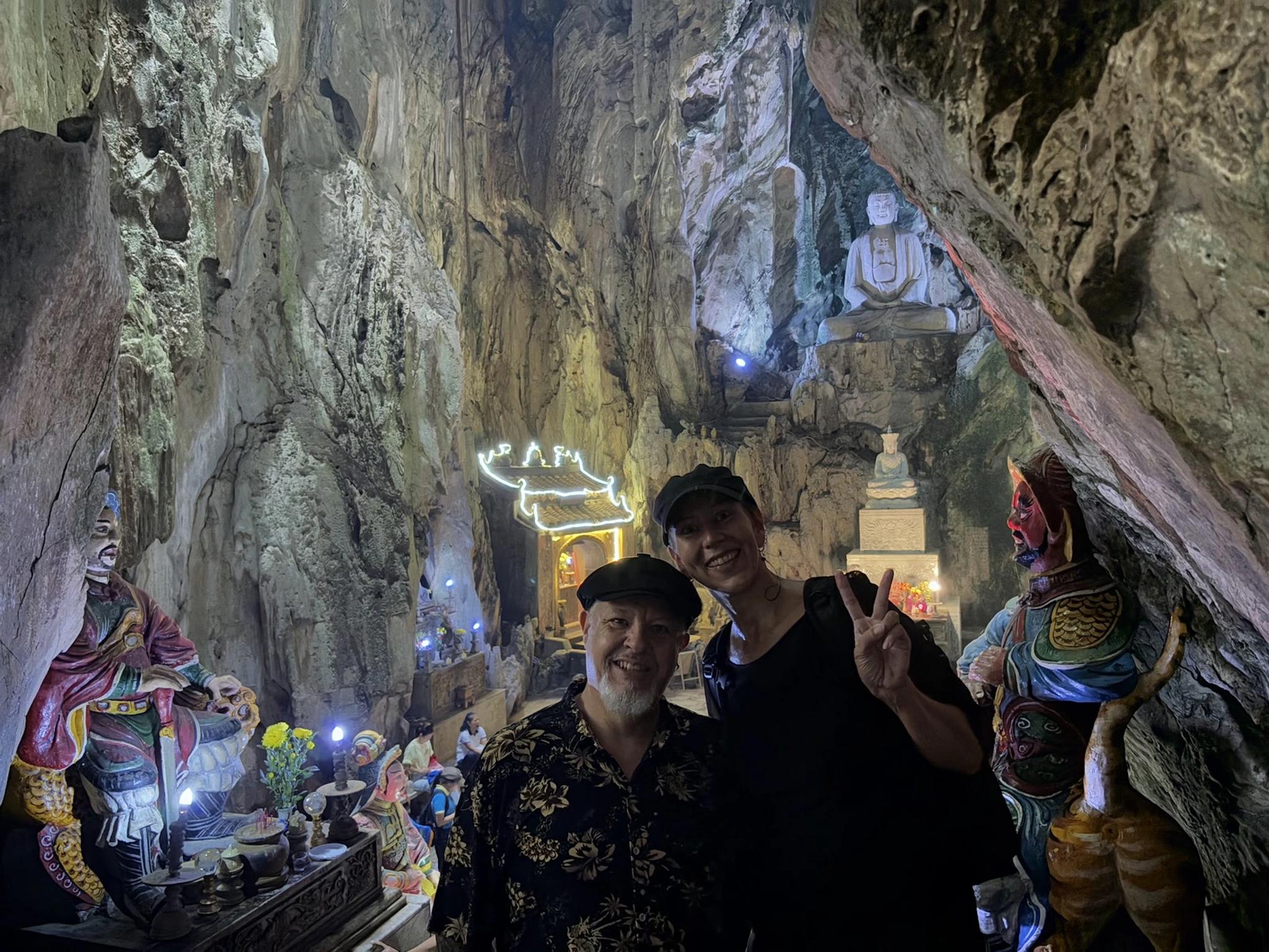 Travellers smiling inside Huyen Khong Cave at the Marble Mountains, with the lit shrine behind them.