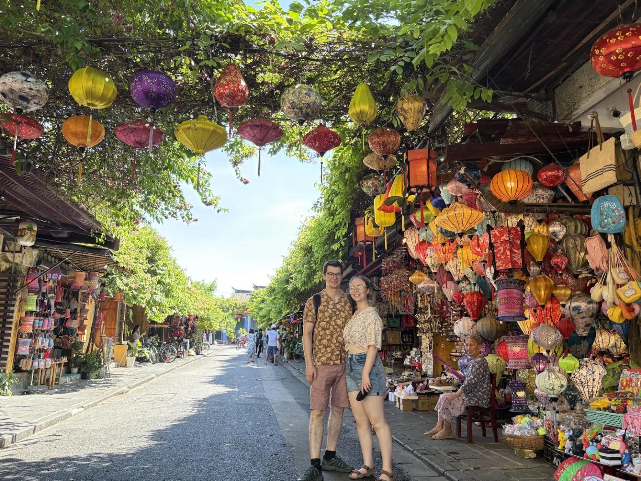 A couple standing before a lantern shop covered by a green trellis in the Old Town.