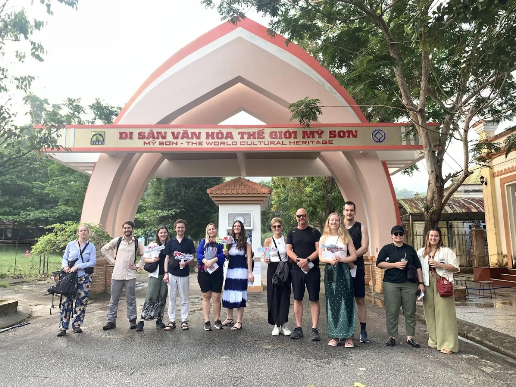 Fingo tour group posing at the My Son Sanctuary entrance gate under the UNESCO World Heritage sign before the private tour starts.